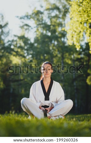 Woman in kimono meditating on the grass in the forest