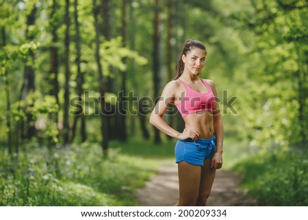 Fitness woman runner relaxing after forest running and working out outdoors in recreation park