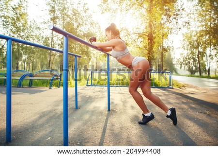 fitness woman relax after workout exercises on bars outdoor. brunette fit girl relax after street training