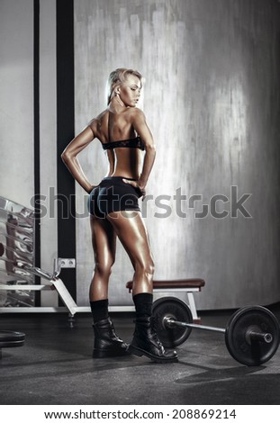 fitness blonde girl posing and prepares for exercising with barbell in gym