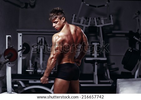 fitness man bodybuilder with muscular back and triceps posing in gym