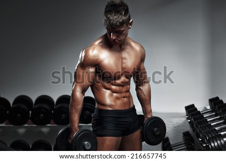 fitness man bodybuilder with muscular torso workout with dumbbells in gym