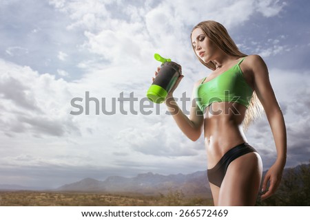 Fitness woman drinking water after running at outdoor Thirsty sport runner resting taking a break with water bottle drink outside after training. Beautiful fit sporty caucasian girl.