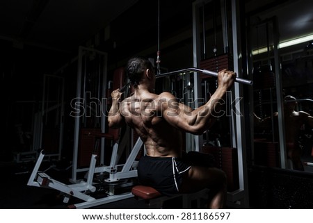 Athlete muscular bodybuilder training back on simulator in the gym