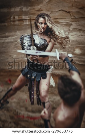 Beautiful strong girl gladiator with sword fights a warrior. Ancient Rome