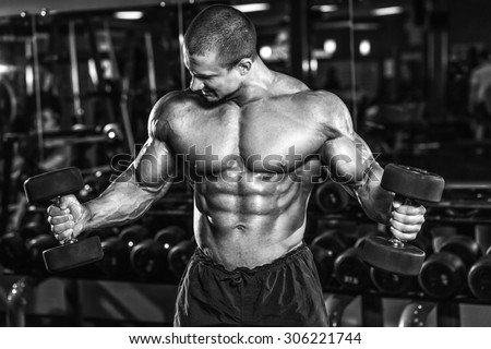 Athlete muscular bodybuilder in the gym training biceps with dumbbell