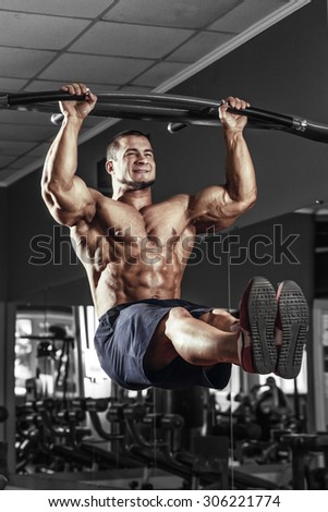 Muscle athlete man in gym making pull-up. Bodybuilder training in gym