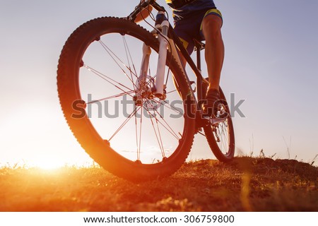 low angle view of cyclist riding with mountain bike on trail at sunset