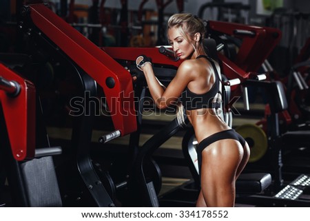 Sexy hot blonde fitness bikini girl with perfect shape body and butt posing and relaxing in gym
