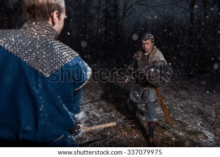 The battle between medieval knights in the style of Game of Thrones in winter forest landscapes. Spear against sword