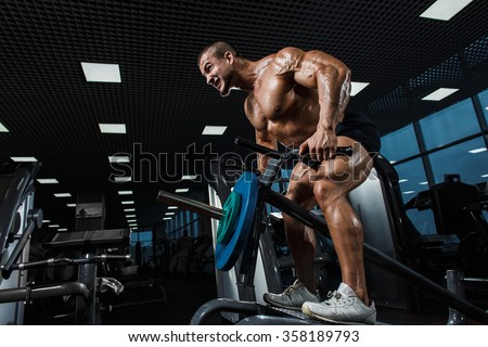 Athlete muscular bodybuilder in the gym training biceps with bar