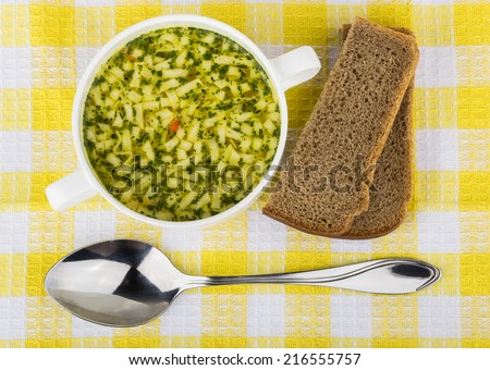 Bowl of soup with pasta, bread and spoon. Top view