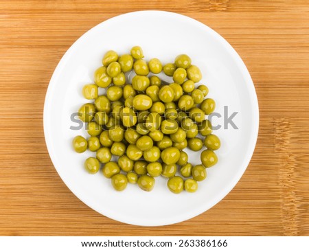 Green peas in plate on bamboo board. Top view
