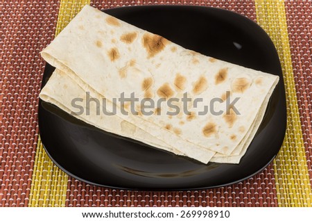 Folded of thin Armenian lavash in black glass plate on bamboo mat