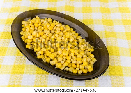 Sweet canned corn in black oval glass dish on tablecloth