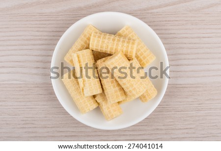 Heap of wafer rolls in glass saucer on table, top view