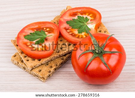Wheat crisp bread and tomato on wooden table