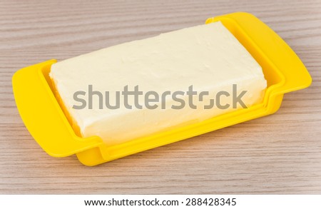 Butter in yellow plastic dish on wooden table