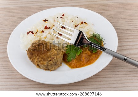 Fried cutlet with rice, squash caviar and greens on table