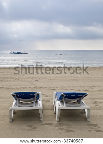 Lonely Mediterranean beach with two chairs looking to the sea