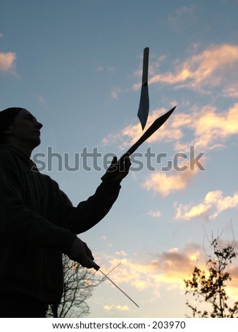 Silhouette of a man juggling knives