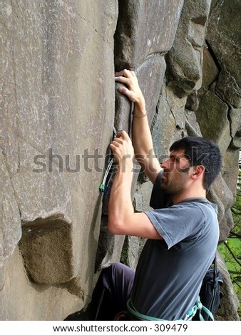 Young fit man climbing up a cliff face