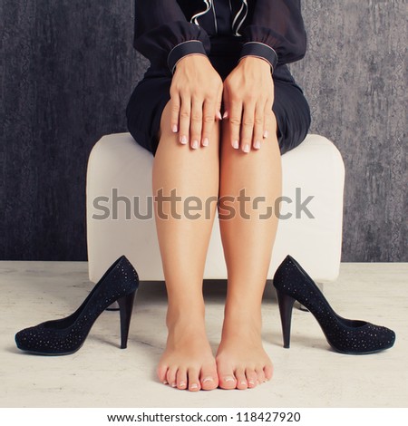 Legs of business woman sitting in black suit with naked feet and shoes