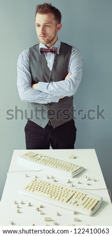 Young computer geek with beard in suit near the table with disassembled keyboards