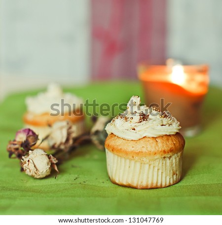 White cupcakes on the green towel with flowers and candles