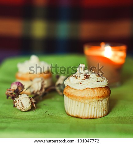 White cupcakes on the green towel with flowers and candles