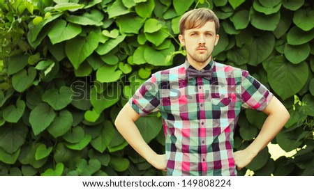 Young fashion man in shirt and bowtie makes his arms akimbo