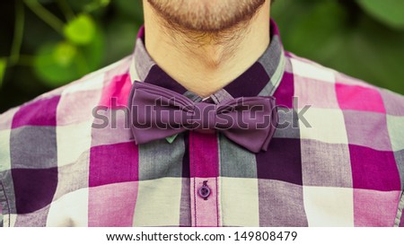 Fashion bearded gentle man in purple bow tie and shirt (hipster style)