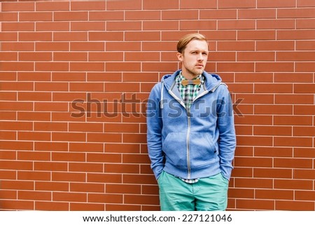 Portrait of fashion young man in casual wear with bowtie, shirt and jacket in front of stoned wall