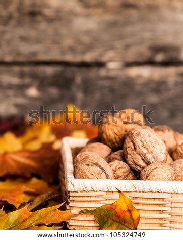 Autumn border from walnuts and fallen leaves on wooden background. Shallow depth of fields