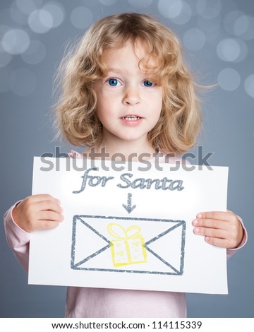 Happy child holding Christmas card with hand drawn letter for Santa Claus and gift