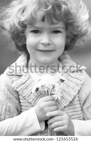 Smiling child holding bunch of flowers. Black and white photo