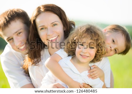 Happy family having fun outdoors in spring field against natural green background