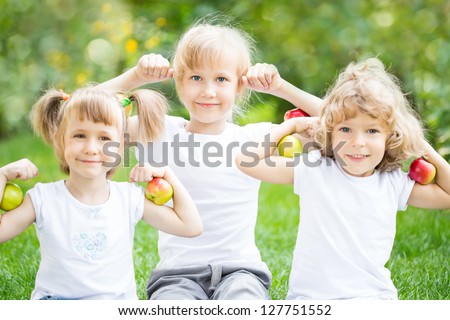 Happy children with apples against spring green background. Fitness concept