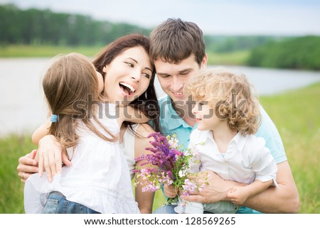 Happy Family With Flowers Having Fun Outdoors In Spring Field