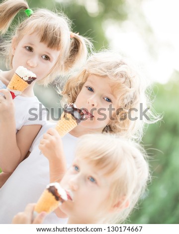 Group of happy children eating ice cream outdoors in summer park