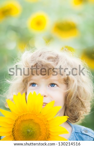 Happy smiling child with sunflower in spring field. Ecology concept