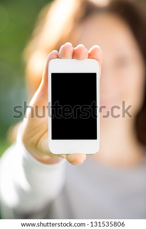 Woman holding smart phone in hand against green spring background