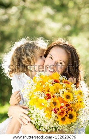 Family with big bouquet of spring flowers. Child kissing woman. Mothers day holiday concept
