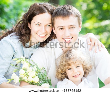Happy family with bouquet of flowers having fun outdoors in spring park against natural green background. Mothers day celebration concept