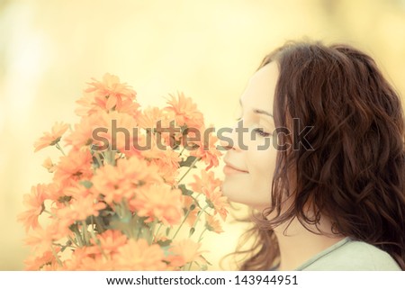 Smiling woman with bouquet of autumn flowers outdoors. Shallow depth of field