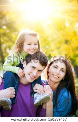 Happy family having fun outdoors in autumn park against golden sunny background