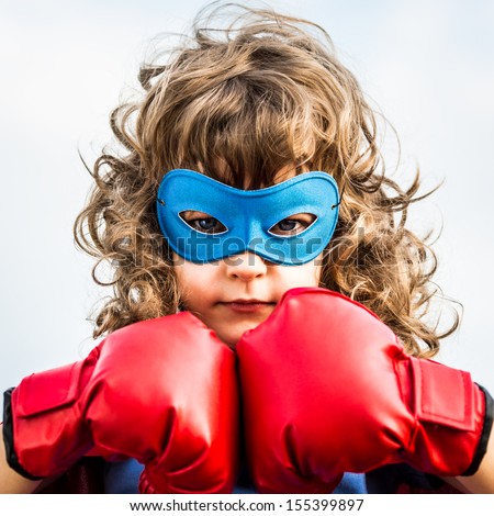 Superhero Kid Wearing Boxing Gloves Against Blue Sky Background. Girl Power And Feminism Concept