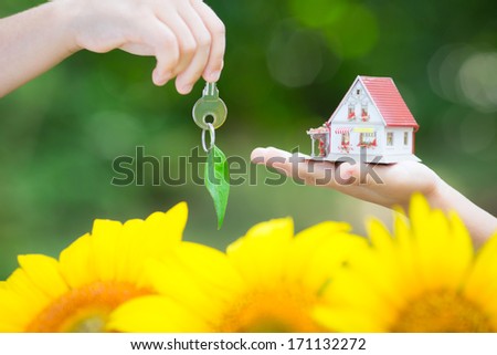 Ecology house and key in hands against green spring background