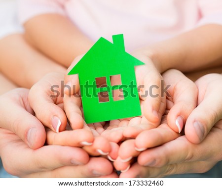 Family holding green paper house in hands. Real estate concept