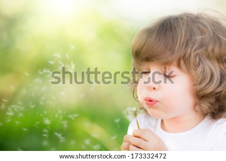 Happy child blowing dandelion outdoors in spring park Happy child blowing dandelion outdoors in spring park